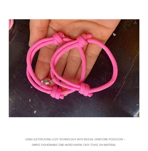 Détail de bracelets de couple tressés roses avec breloques boules magnétiques argent