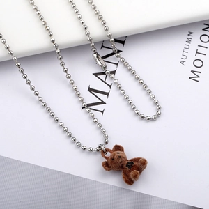 Brown flocked teddy bear necklace with silver beaded chain on a minimalist white background