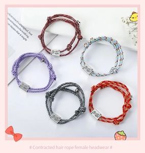 Detail view of colorful braided magnetic couple bracelets set with small metal charms