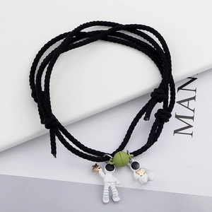 Detail of magnetic astronaut couple bracelets with woven rope and small planet charms