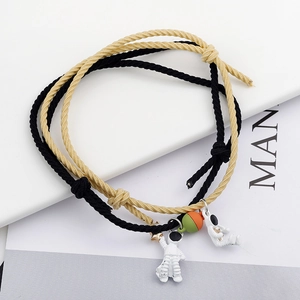 Detail of woven astronaut couple bracelets with adjustable cords and charms