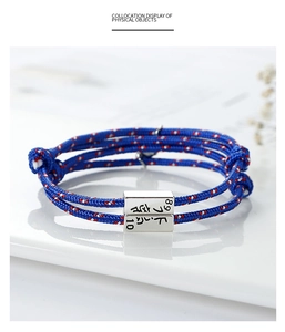 Detail of adjustable blue woven rope bracelet with engraved silver metal block charm