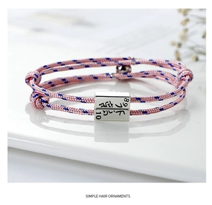 Macro detail of magnetic couple bracelets featuring engraved silver sliders and braided rope