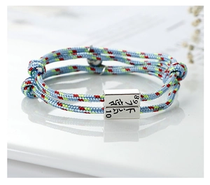 Detailed macro shot of blue woven couple bracelets with silver magnetic charms and engraving