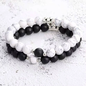 Detail of white turquoise and matte black agate beaded bracelets with metal charms