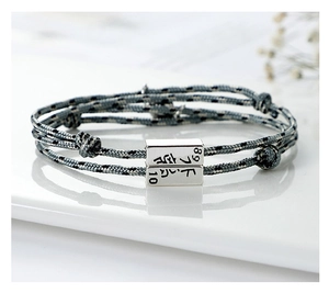 Detail of woven rope bracelet with 89 and 10 engraved silver magnetic charms