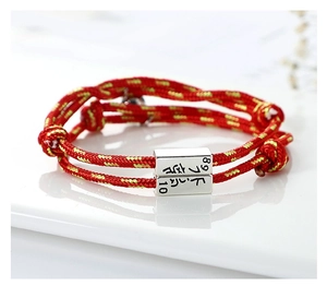 Detailed close-up of woven red cord bracelet with engraved silver magnetic metal clasps