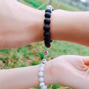 Close-up of magnetic heart attraction bracelets on hands with natural grass background