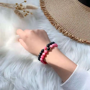 Detailed view of beaded couple bracelets with matte black and pink marble textures on wrist