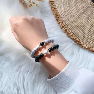 Detail of minimalist black and white beaded couple bracelets on soft fur background
