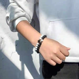 Detail of matte black and white marble bead bracelets worn together in natural sunlight