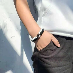 Close-up of matte black and white marble bead bracelets worn on wrist in outdoor light