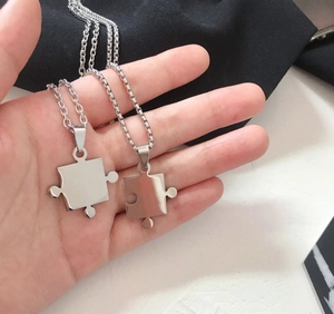 Nahaufnahme der Puzzleteil-Anhänger mit poliertem Silber-Finish auf schwarzem Hintergrund