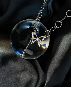 Silver butterfly pendant necklace displayed on a glass ball with black silk background