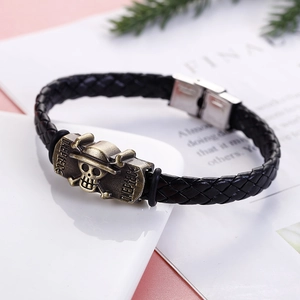 Close-up of braided leather bracelet featuring a bronze One Piece skull charm buckle
