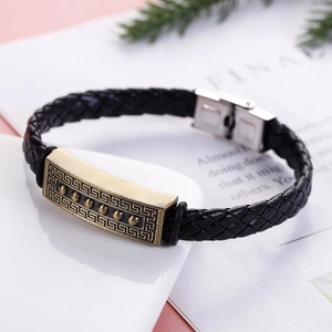 Detail of black braided leather bracelet with bronze pattern plate and stainless steel clasp