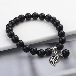 Dettaglio del bracciale di perline nere con un ciondolo a forma di foglia in argento puro