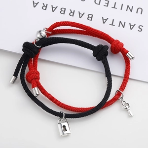 Détail des breloques serrure et clé magnétiques sur bracelets de couple tressés rouge et noir