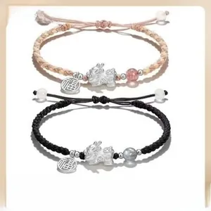 Detail of woven Pixiu bracelet with silver charms and natural stone beads on a warm background
