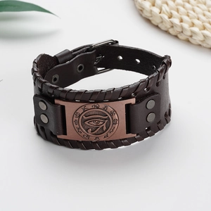 Detail of vintage brown leather bracelet with Eye of Horus bronze metal plaque and rivet studs