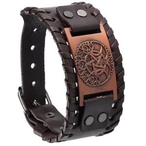 Detail of vintage brown leather wide cuff with woven edges and Nordic totem metal plate