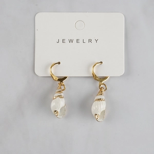 Detail of natural white shell earrings with golden edges and metal hooks on a display card