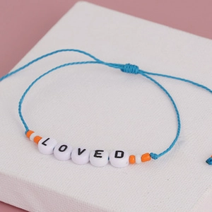 Detail of woven blue rope bracelet with LOVED letter beads and adjustable sliding knot