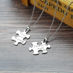 Puzzle-Halsketten für Paare in Silber mit I love you Gravur auf grauem Holzhintergrund