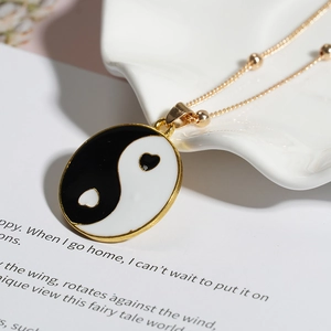 Macro del ciondolo Yin Yang placcato oro con dettagli in smalto a forma di cuore