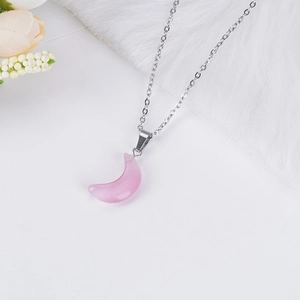 Detalle de un colgante de luna rosa translúcido en una fina cadena de plata elegante