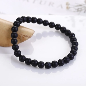 Detail of 6mm matte black beads bracelet with unique white eye texture on one stone