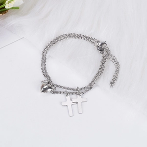 Bracelets de couple avec cœur magnétique argenté et pendentifs croix sur fond blanc
