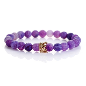 Macro shot of purple weathered agate beads with a golden rhinestone crown charm