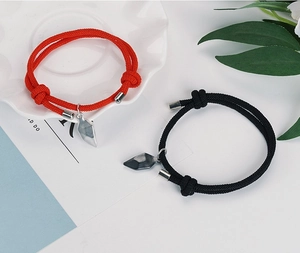 Detail of red and black magnetic couple bracelets with adjustable woven rope on white plate