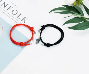 Detail of magnetic heart charms on braided couple bracelets in red and black