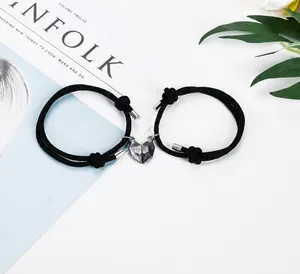 Detail of couple bracelets with magnetic heart charm on woven ropes for distance lovers