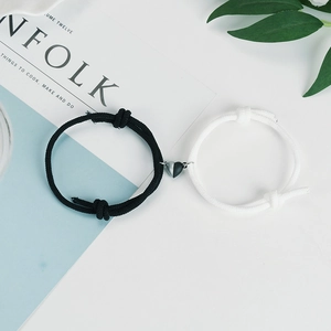 Magnetic heart couple bracelets with black and white woven ropes on a clean white background