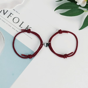 Detailed macro of burgundy braided couple bracelets with silver-black magnetic heart clasp