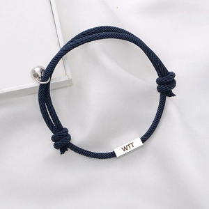 Detail of blue braided couple bracelet featuring engraved silver metal plaque and charms