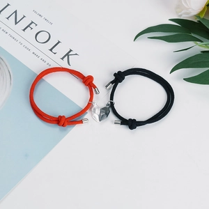 Magnetische koppelarmbanden van rood en zwart gevlochten touw op een wit bureau