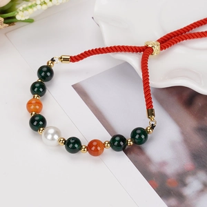 Gros plan du bracelet perlé réglable fait main avec cordon rouge et boucle coulissante dorée