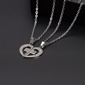 Detail of interlocking heart pendants with cross cutout and engraved message for couples