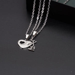 Macro detail of silver titanium steel heart and LOVE pendant necklaces for couples