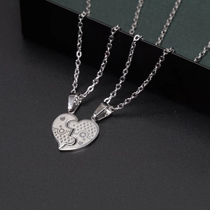 Close-up of puzzle heart couple necklaces with gender symbols in polished steel