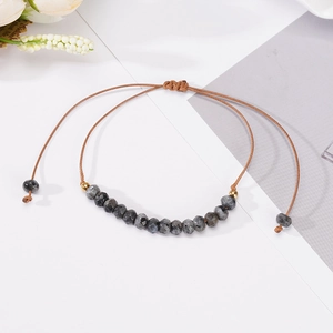 Detail view of 6mm faceted natural stone beads on a brown braided adjustable cord