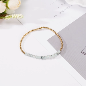Detalle de cuentas doradas 4mm y pulsera de piedras naturales azul claro en fondo blanco