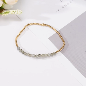 Detalle de cuentas doradas de 4mm y cuentas de piedra de luna gris en una pulsera fina