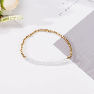 Vista de primer plano de cuentas doradas y gemas blancas facetadas en una pulsera minimalista