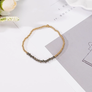 Detalle de pulsera de cuentas doradas de 4mm con piedras de hematita y cordón elástico