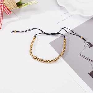Adjustable black cord bracelet with polished gold stainless steel beads on white background